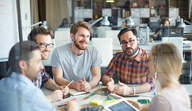 Group of Employees Sitting at Table Smiling with Group Insurance in Loveland, Windsor, Greeley, Fort Collins, Longmont