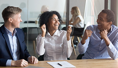 Men and Woman Laughing at Table with Group Health Benefits in Fort Collins, Greeley, Longmont, Loveland, and Windsor